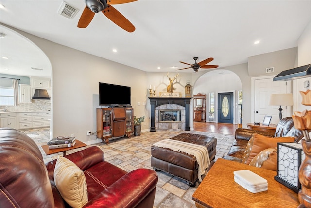 living area with visible vents, arched walkways, baseboards, a fireplace, and recessed lighting