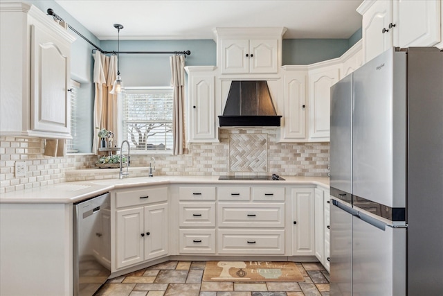 kitchen with custom range hood, appliances with stainless steel finishes, hanging light fixtures, white cabinetry, and a sink