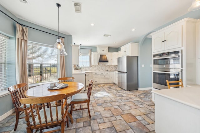 dining area featuring arched walkways, stone finish floor, visible vents, and baseboards