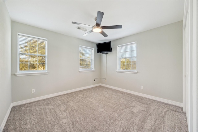 unfurnished room with carpet floors, baseboards, visible vents, and a ceiling fan