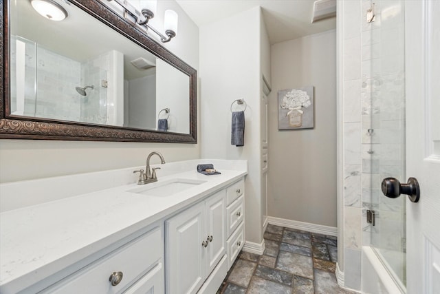 bathroom featuring stone tile floors, baseboards, combined bath / shower with glass door, and vanity