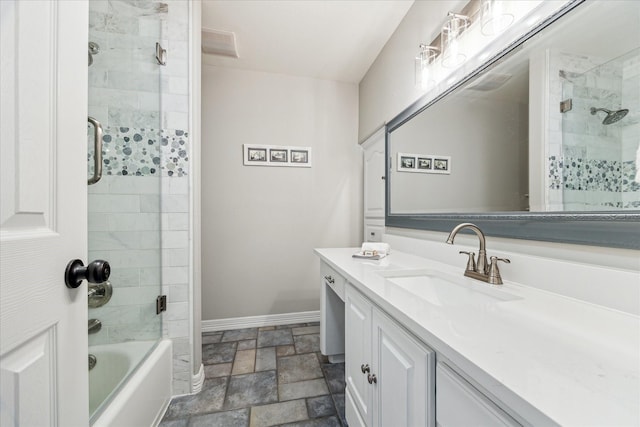 full bath with shower / bath combination with glass door, stone tile floors, baseboards, and vanity