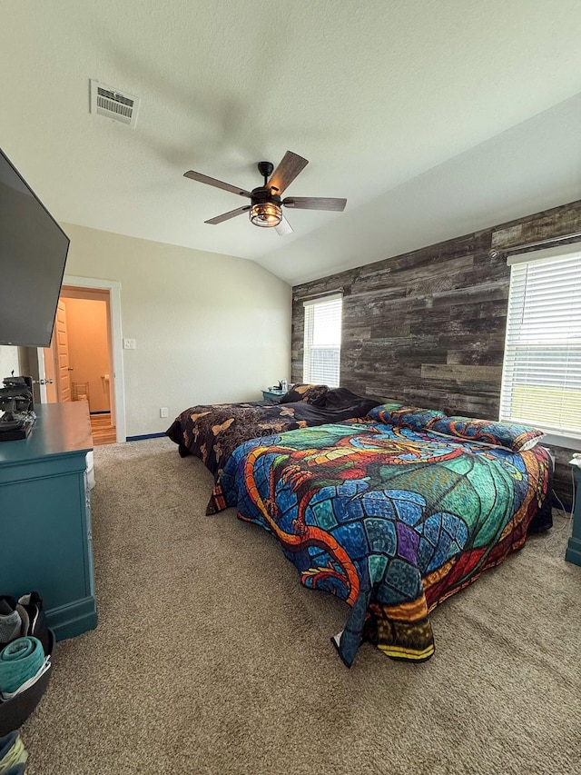 bedroom featuring carpet floors, lofted ceiling, visible vents, wooden walls, and a textured ceiling