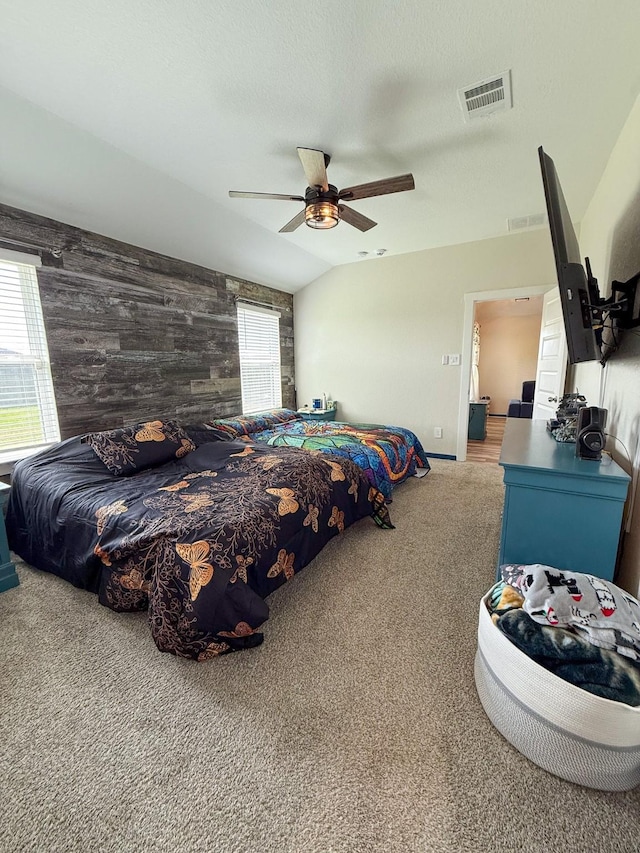 carpeted bedroom with wood walls, an accent wall, visible vents, and a textured ceiling