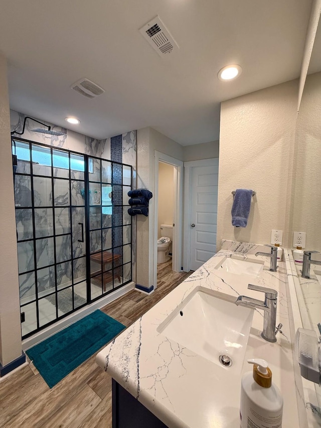 full bath featuring visible vents, toilet, a sink, wood finished floors, and walk in shower