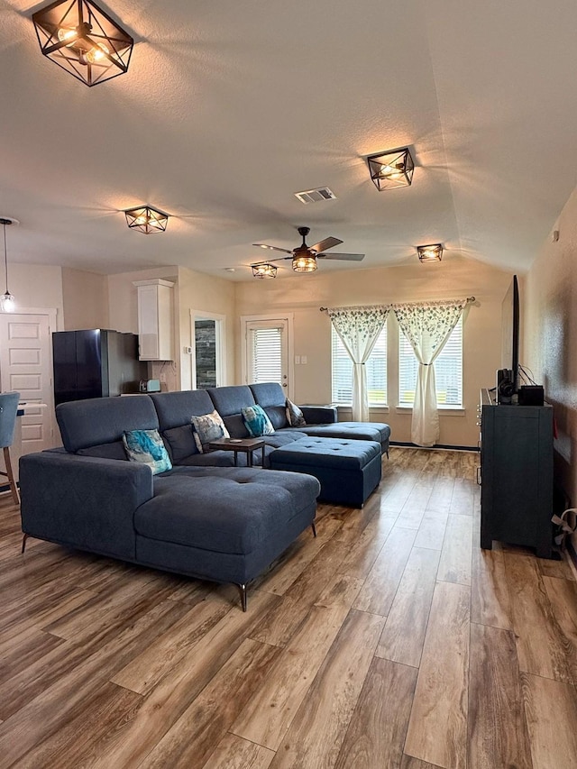 living room with a ceiling fan, visible vents, a textured ceiling, and wood finished floors