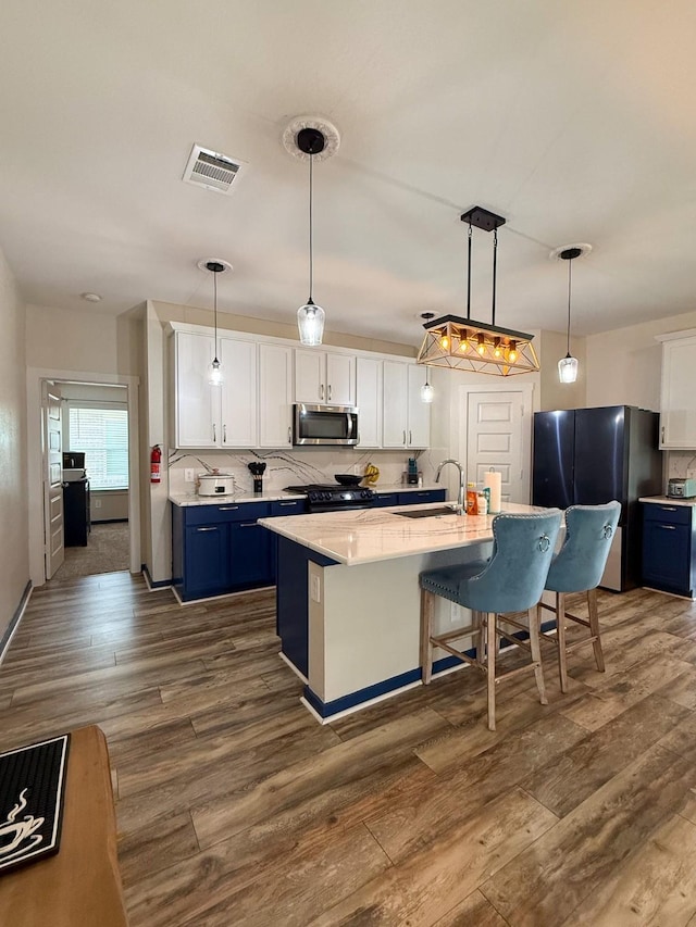 kitchen featuring visible vents, appliances with stainless steel finishes, white cabinets, and dark wood-style flooring