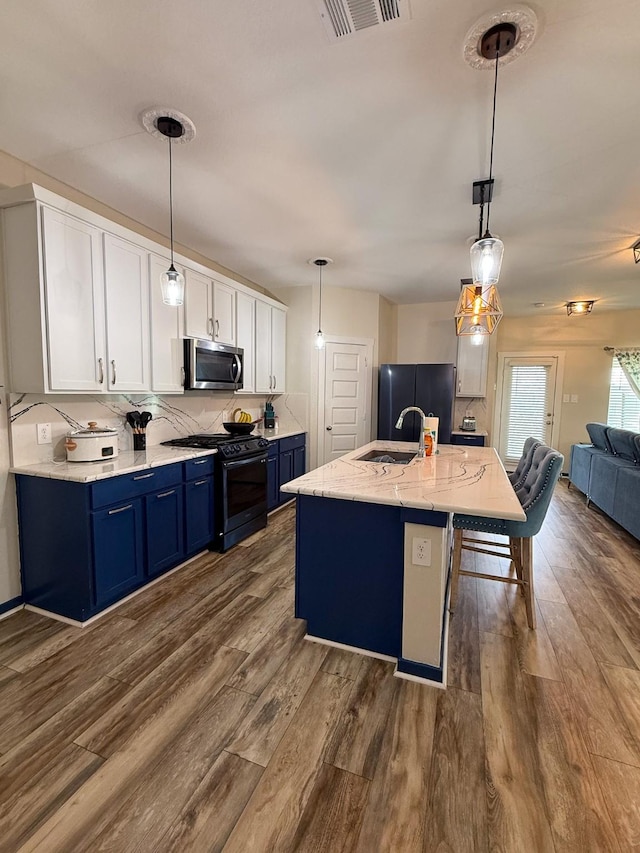 kitchen featuring visible vents, dark wood finished floors, blue cabinets, black appliances, and a sink