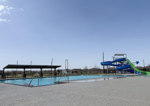 pool featuring fence, a water slide, and a patio