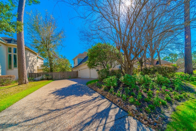 view of front facade featuring fence, driveway, an attached garage, and stucco siding