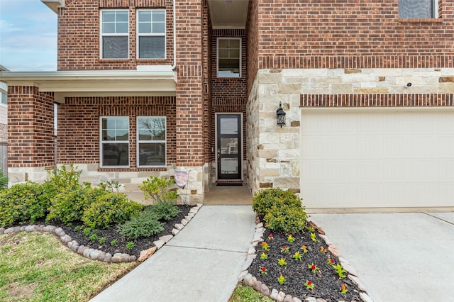 property entrance with a garage, brick siding, and stone siding