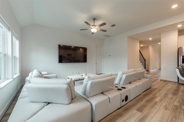 living area featuring visible vents, baseboards, stairway, lofted ceiling, and light wood-style flooring