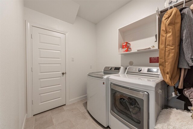 clothes washing area featuring light tile patterned floors, baseboards, laundry area, and washer and clothes dryer