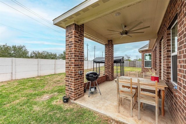 view of patio with grilling area, outdoor dining space, a ceiling fan, and a fenced backyard