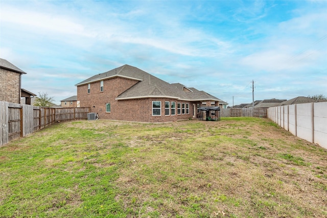 rear view of property with brick siding, a fenced backyard, central air condition unit, and a yard