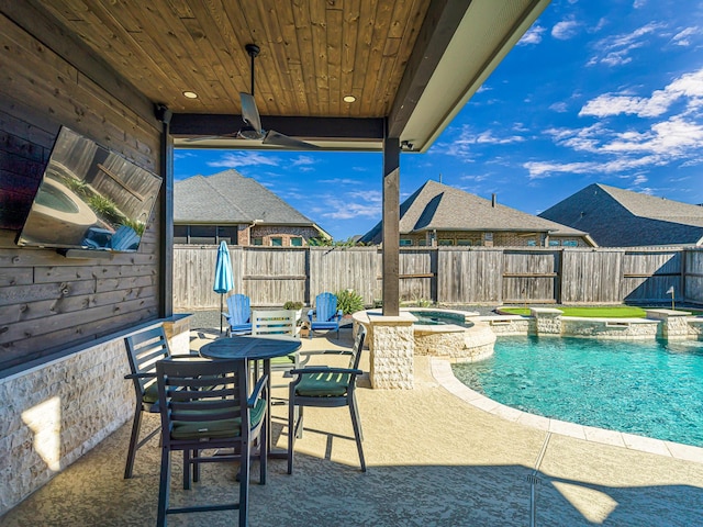 view of pool with a pool with connected hot tub, a fenced backyard, and a patio