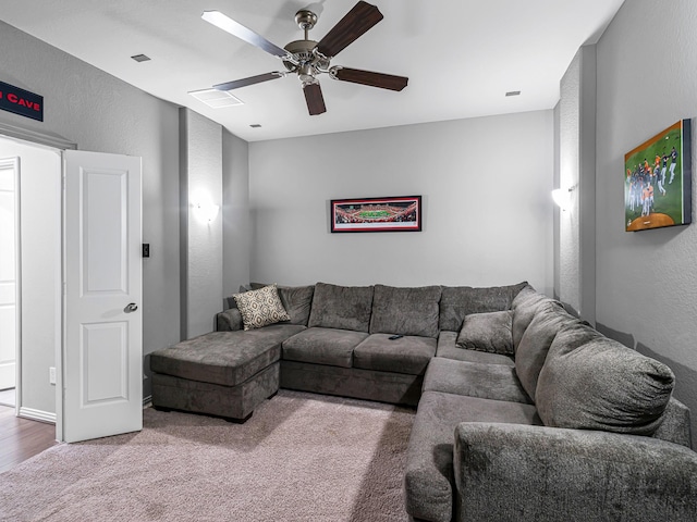 carpeted living area featuring ceiling fan, visible vents, and a textured wall