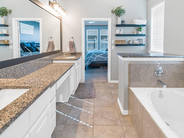 ensuite bathroom with connected bathroom, a sink, a healthy amount of sunlight, a bath, and double vanity