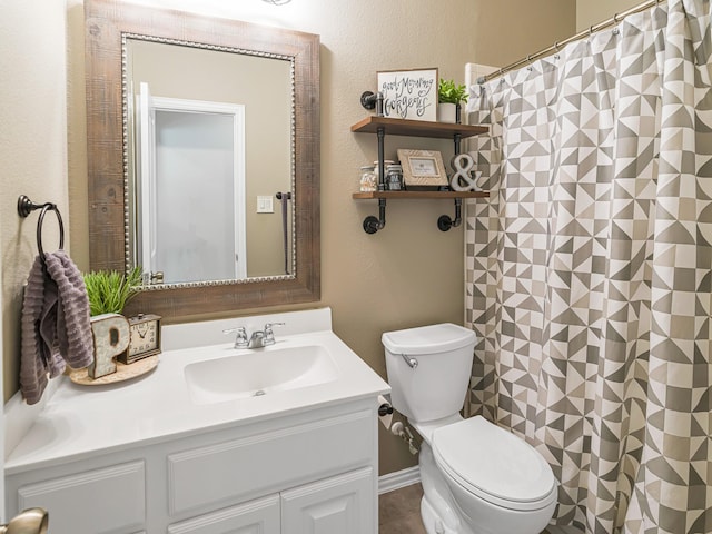 bathroom with a textured wall, vanity, toilet, and a shower with curtain