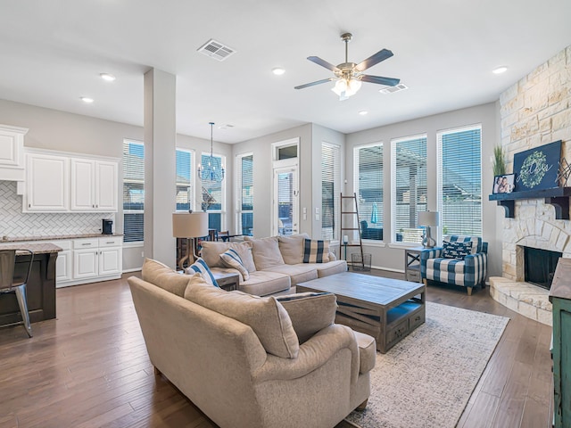 living room featuring dark wood-style floors, visible vents, and a fireplace