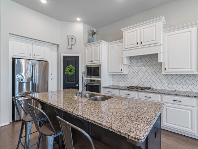 kitchen with stainless steel appliances, dark wood-style flooring, decorative backsplash, and light stone countertops