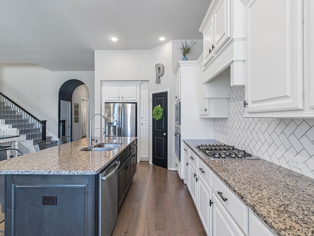 kitchen featuring light stone countertops, white cabinetry, appliances with stainless steel finishes, and a sink