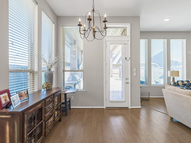 entryway featuring baseboards, wood finished floors, and a notable chandelier