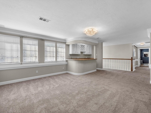 7714 Hertfordshire Dr, Spring, TX 77379 - unfurnished living room with light colored carpet, a textured ceiling, crown molding, and baseboards
