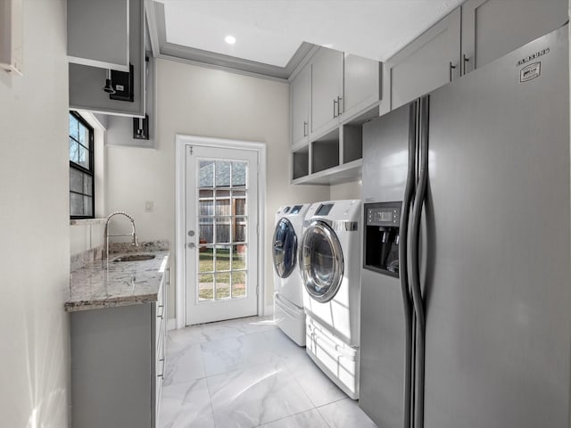 7714 Hertfordshire Dr, Spring, TX 77379 - laundry area with separate washer and dryer, light marble finish floors, cabinet space, healthy amount of natural light, and ornamental molding