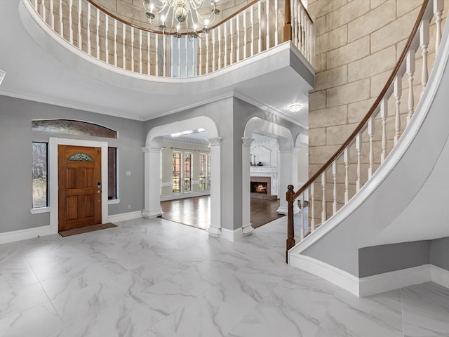 entryway featuring marble finish floor, decorative columns, a high ceiling, and baseboards