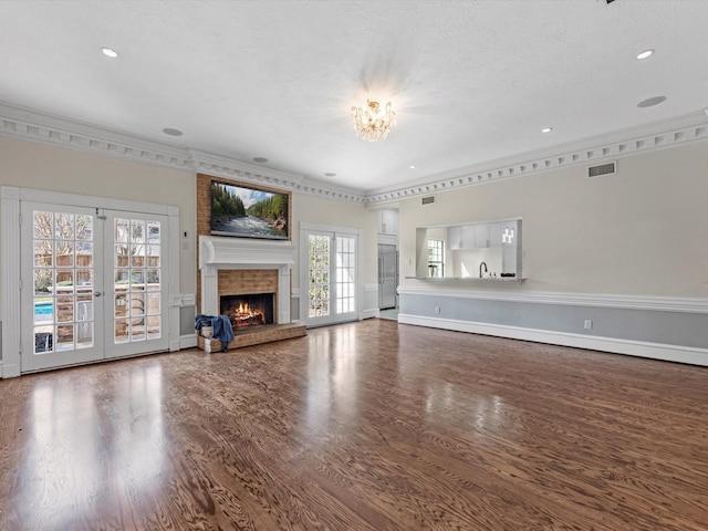7714 Hertfordshire Dr, Spring, TX 77379 - unfurnished living room with wood finished floors, a chandelier, a brick fireplace, ornamental molding, and a textured ceiling
