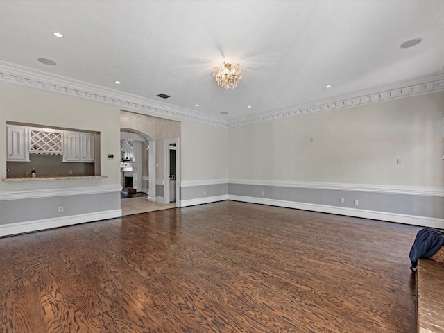 unfurnished living room featuring ornamental molding, arched walkways, and wood finished floors