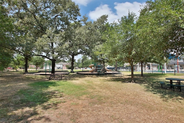 view of home's community with playground community, fence, and a lawn