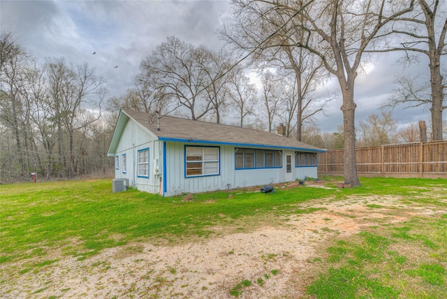 view of side of home with central air condition unit, fence, and a yard