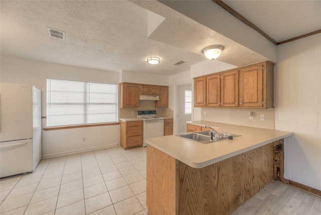 kitchen with white appliances, visible vents, light countertops, under cabinet range hood, and a sink