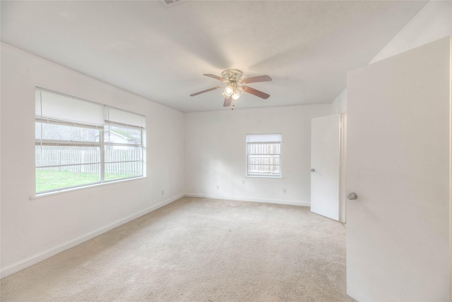 carpeted spare room featuring ceiling fan and baseboards