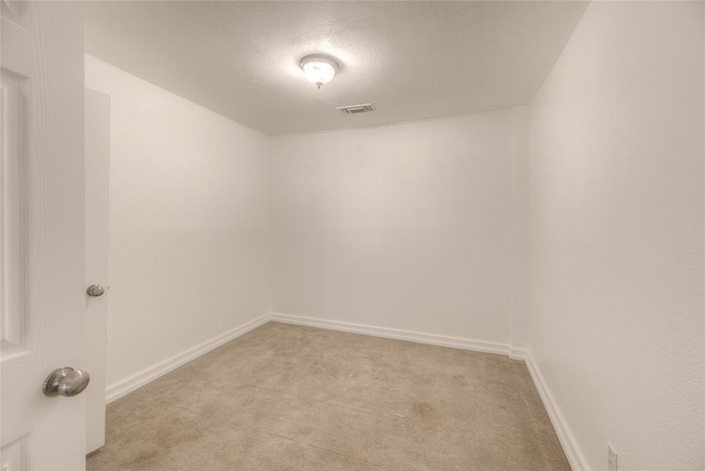 spare room featuring a textured ceiling, baseboards, visible vents, and light colored carpet