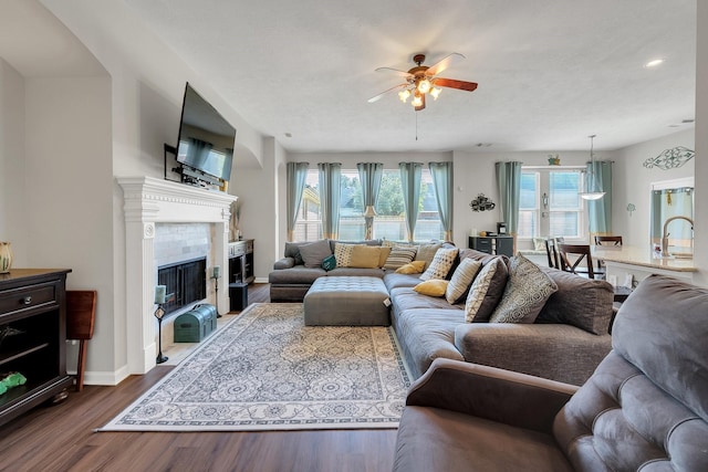 living room featuring baseboards, dark wood finished floors, a ceiling fan, and a tile fireplace