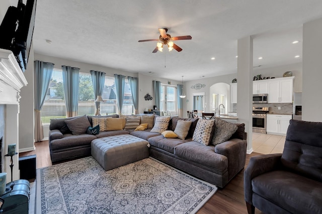 living area featuring arched walkways, plenty of natural light, and light wood-style flooring