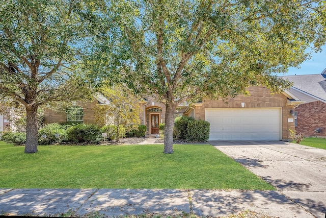 view of property hidden behind natural elements featuring concrete driveway, a front lawn, an attached garage, and brick siding