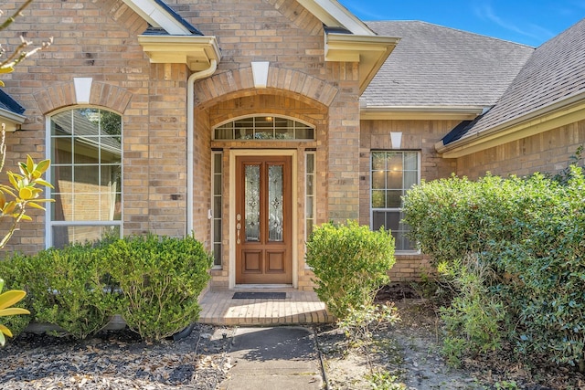 property entrance with brick siding and roof with shingles