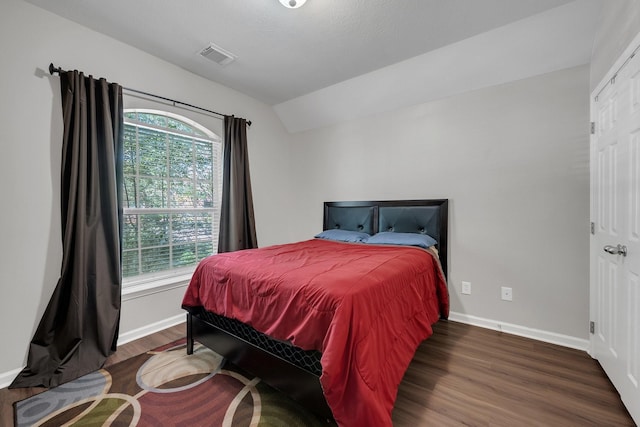 bedroom featuring vaulted ceiling, wood finished floors, visible vents, and baseboards