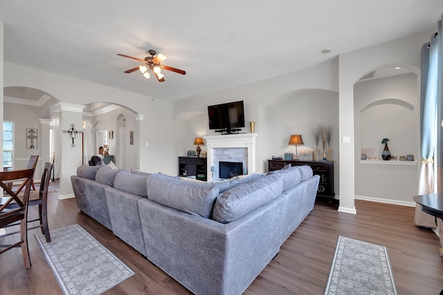 living room with ceiling fan, a fireplace, visible vents, baseboards, and dark wood finished floors