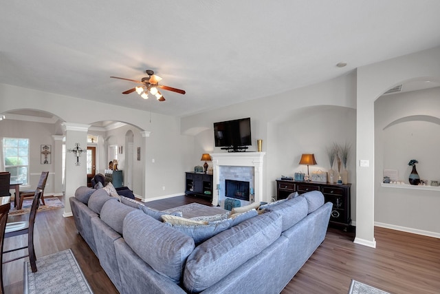 living room featuring dark wood-style flooring, a tiled fireplace, and baseboards