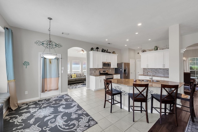 kitchen with arched walkways, light tile patterned floors, visible vents, appliances with stainless steel finishes, and a sink