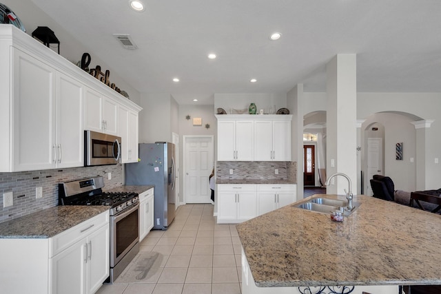 kitchen with arched walkways, visible vents, appliances with stainless steel finishes, white cabinets, and a sink