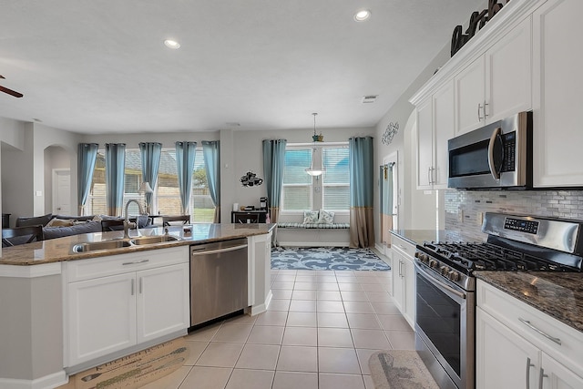 kitchen with light tile patterned floors, tasteful backsplash, appliances with stainless steel finishes, open floor plan, and a sink