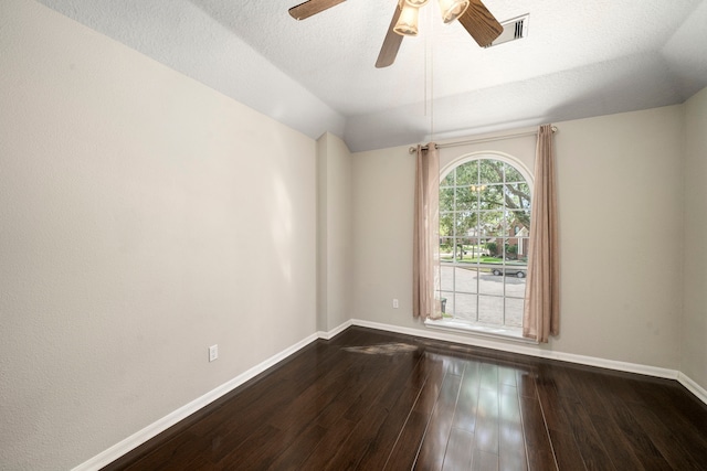 empty room with visible vents, baseboards, dark wood finished floors, lofted ceiling, and a textured ceiling