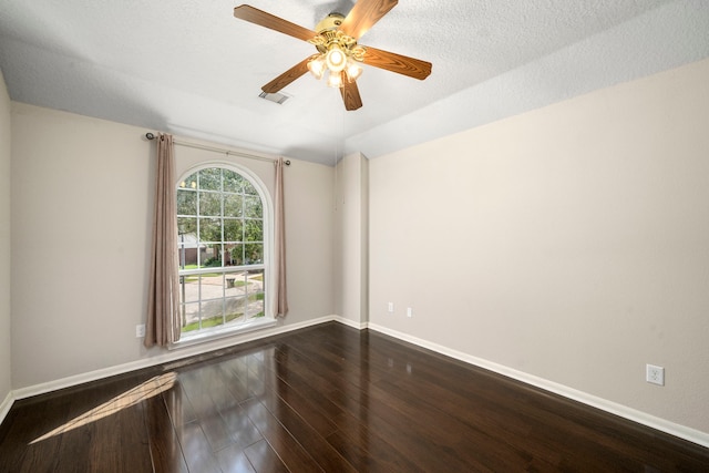 spare room featuring a ceiling fan, dark wood-style flooring, visible vents, and baseboards