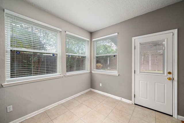 interior space featuring light tile patterned floors, baseboards, and a textured ceiling